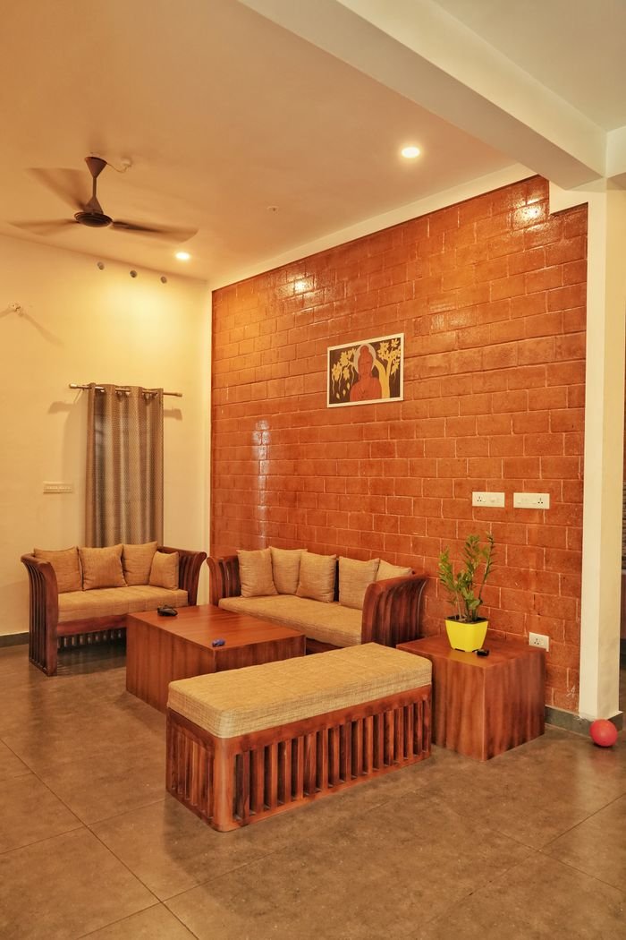 Warm and inviting living room featuring wooden furniture and a brick accent wall in Hyderabad, India.