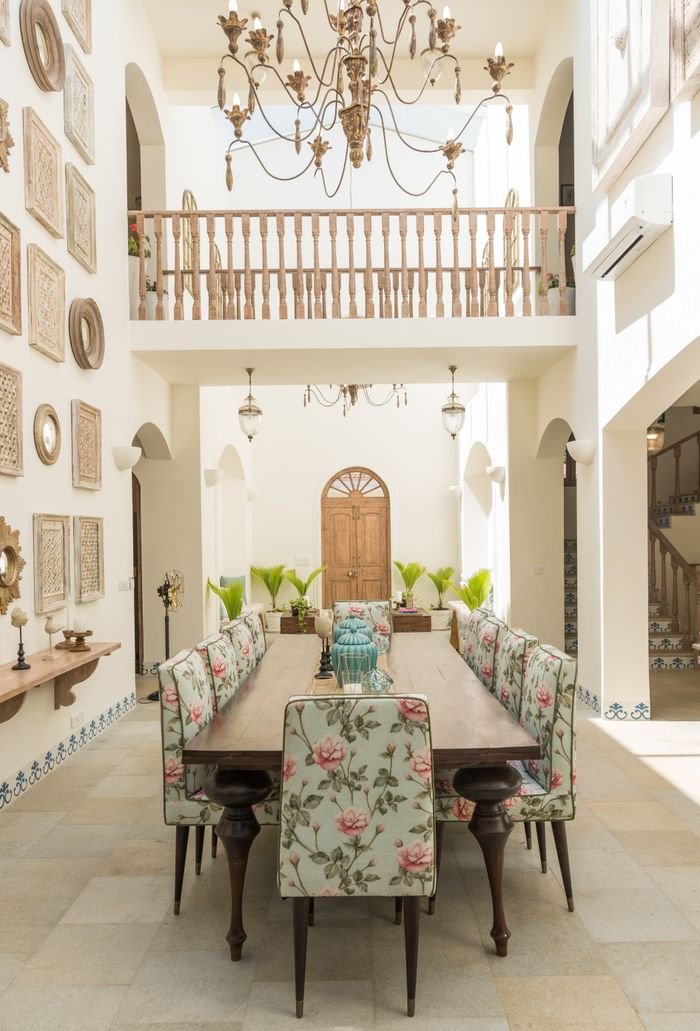 Luxurious dining room featuring floral-print chairs, chandelier, and artistic decor in a spacious villa in Hyderabad and Andhra Pradesh.